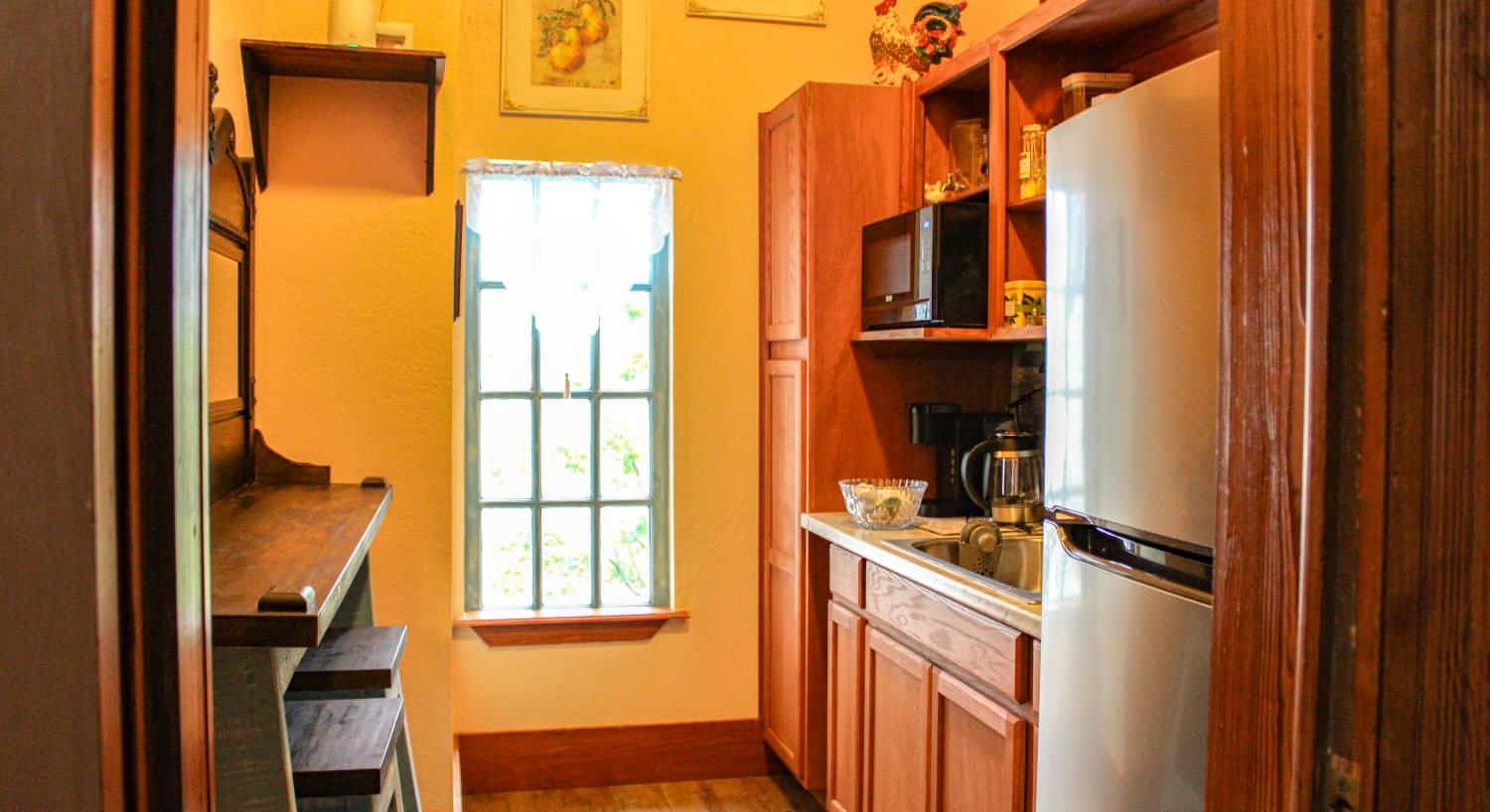 Butler's pantry with wooden cabinets, sink, microwave, and white refrigerator