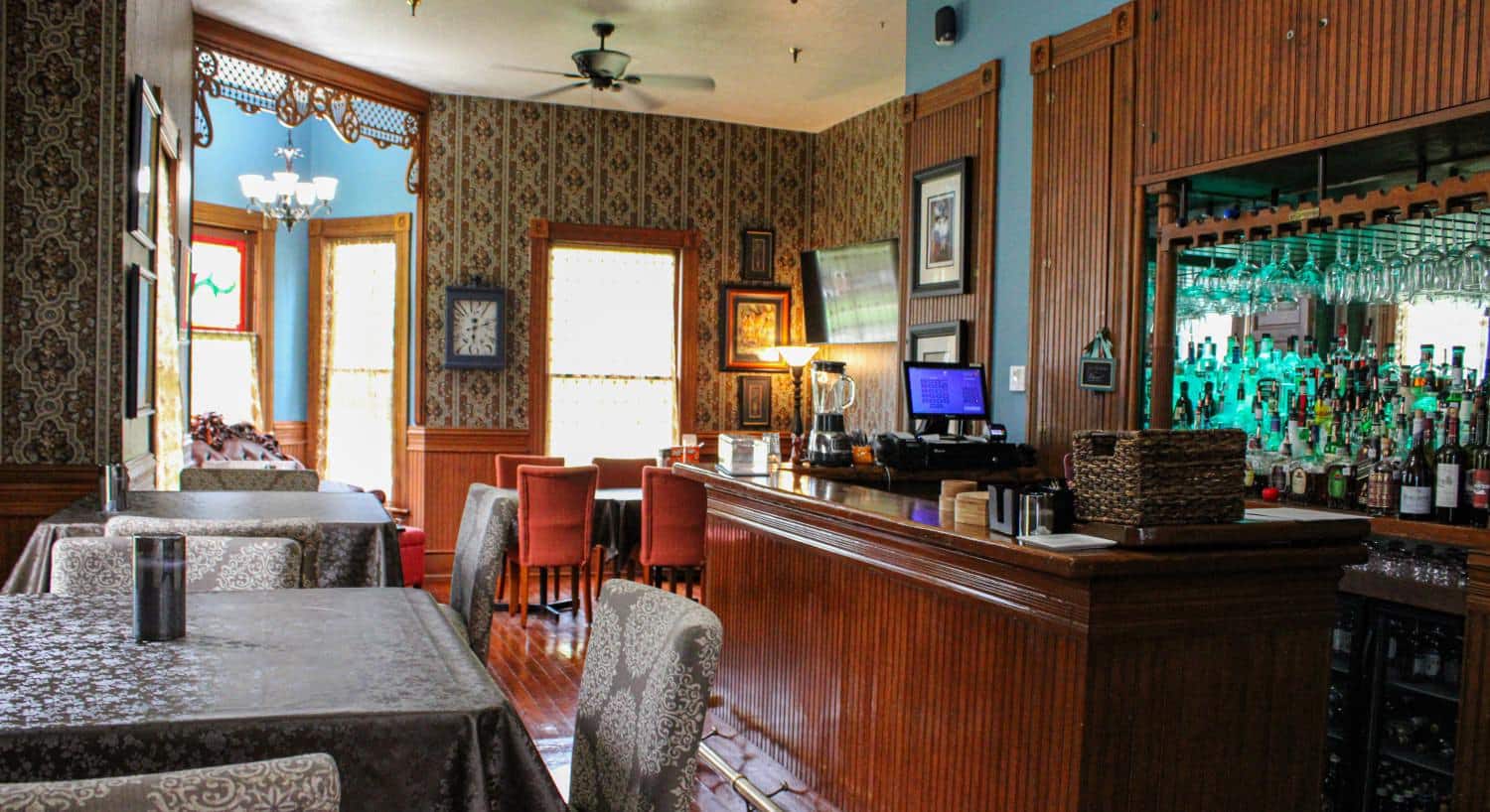 Restaurant area with wooden bar, hardwood flooring, and multiple tables with chairs