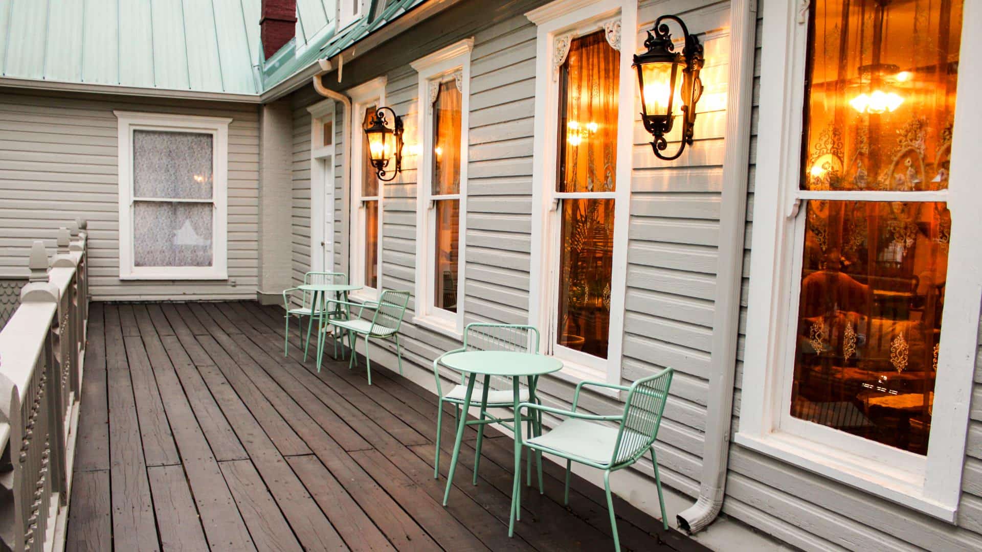 Exterior view of property's deck with light-green painted metal patio chairs and tables