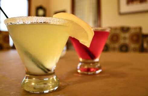 Close up view of two cocktail drinks, one light yellow and another light pink