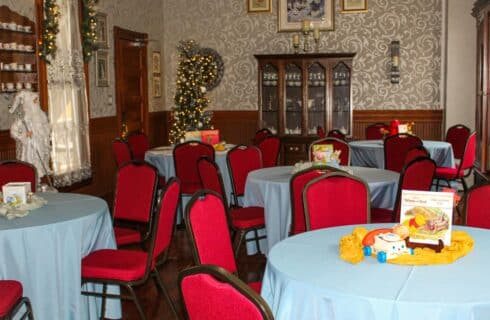 Dining room set up with Christmas decorations, tables with blue tablecloths, and red chairs