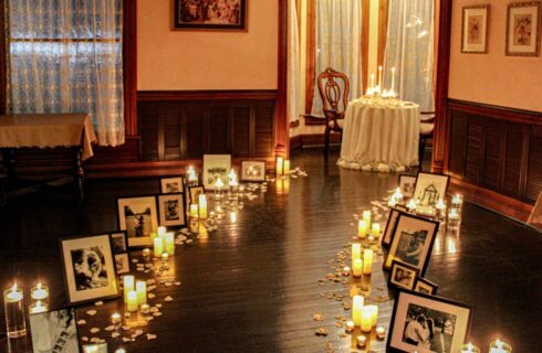 Dining room with hardwood floor decorated with framed photos, candles, and rose petals in a path toward a table set for two